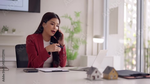 Asian real estate agent client phone call discussing property home sales professional business communication modern office setting