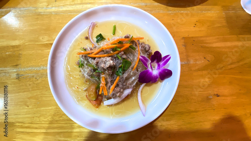 Thai glass noodle salad with fresh herbs on a white ceramic plate, flat lay view.