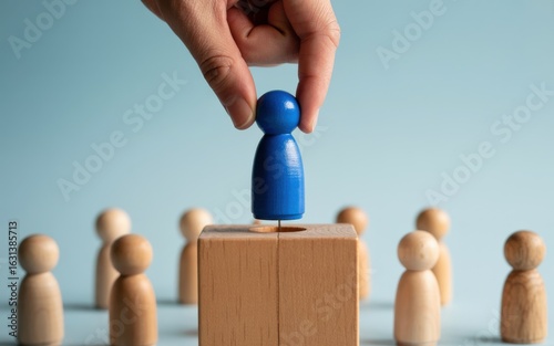 Hand selecting a blue figure for a leadership role, symbolizing business recruitment, promotion, and management.