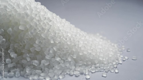 Close up of white plastic pellets flowing, representing industry and manufacturing.
