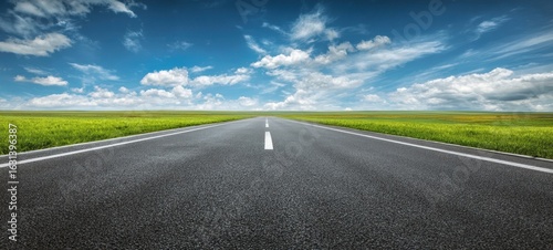 The endless road stretching towards a scenic horizon under a bright blue sky.
