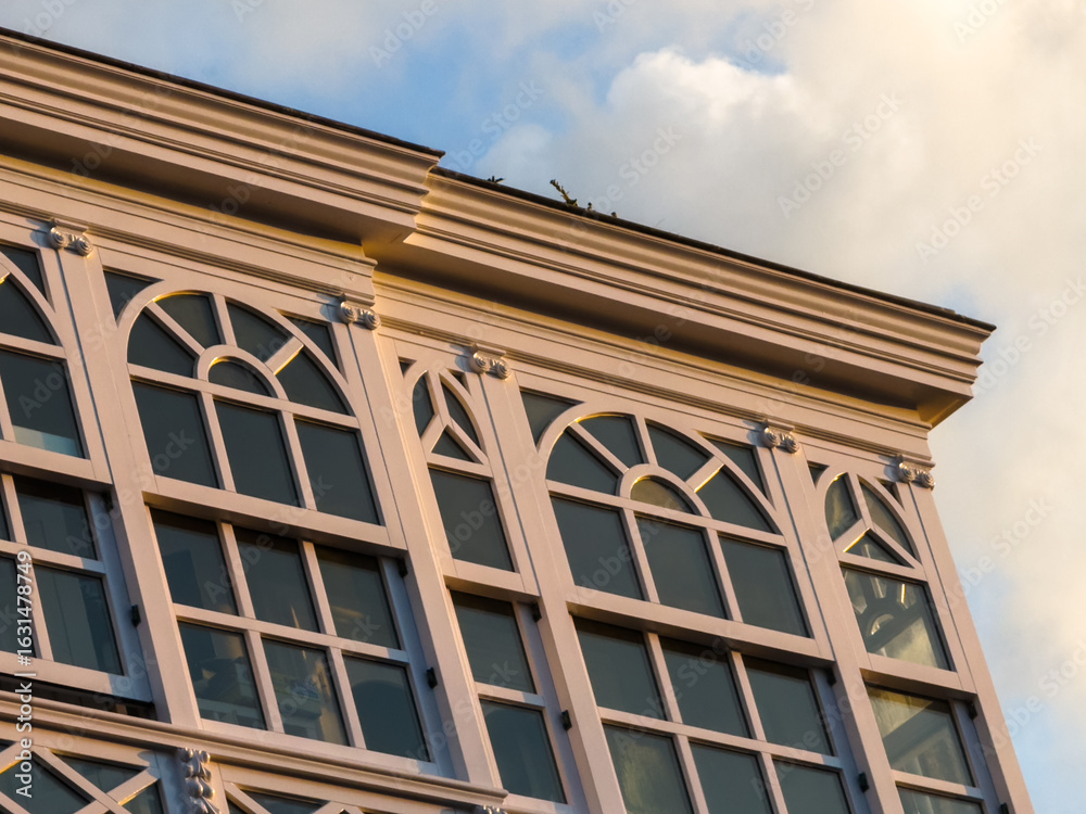 Fototapeta premium Ornate building facade with arched windows in warm sunset light