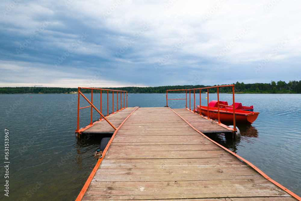 Obraz premium Pomost dla łodzi na jeziorze w lecie podczas pochmurnej pogody.
