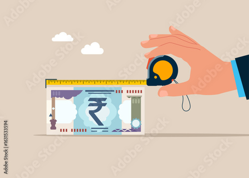 Hand hold measure tape and measures the length of the bill rupee banknote. Concept of investment, wealth, spending, inflation and loss of savings. Money measured with a measure tape.