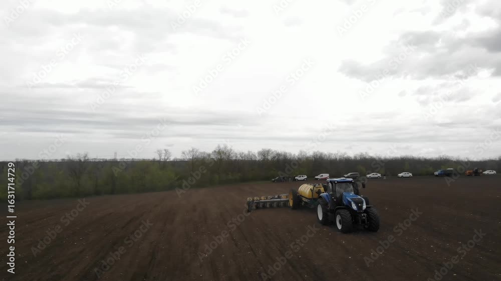 Blue Tractor Sowing Sunflower Seeds with Yellow Planter in Ukraine Blue Tractor Sowing Sunflower Seeds with Yellow Planter in Ukraine