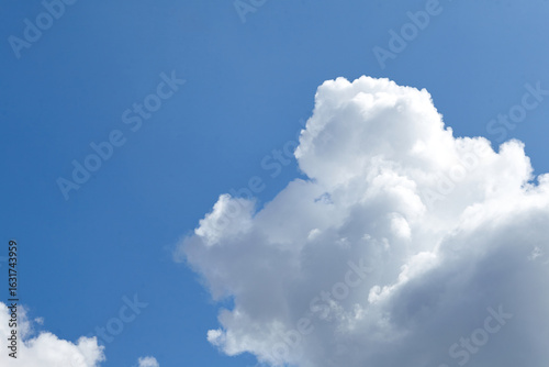 Canvas-taulu Fluffy white clouds scattered across a bright blue sky, creating a serene and tr