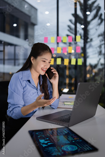 business woman using smartphone and working on laptop at night office.
