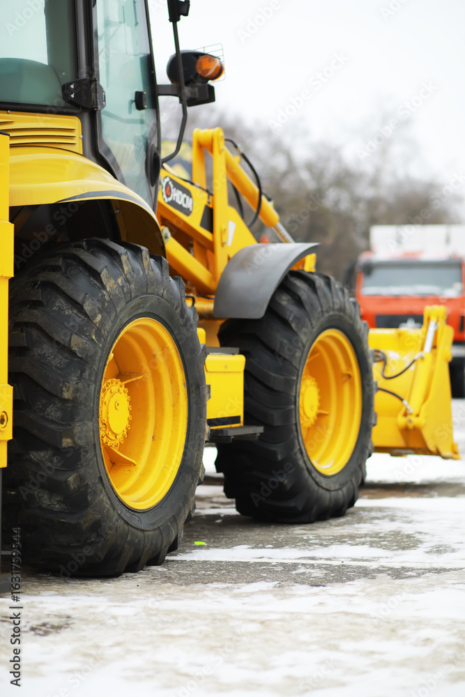 Obraz premium Yellow Construction Loader with Snow-Covered Ground and Trees in Background
