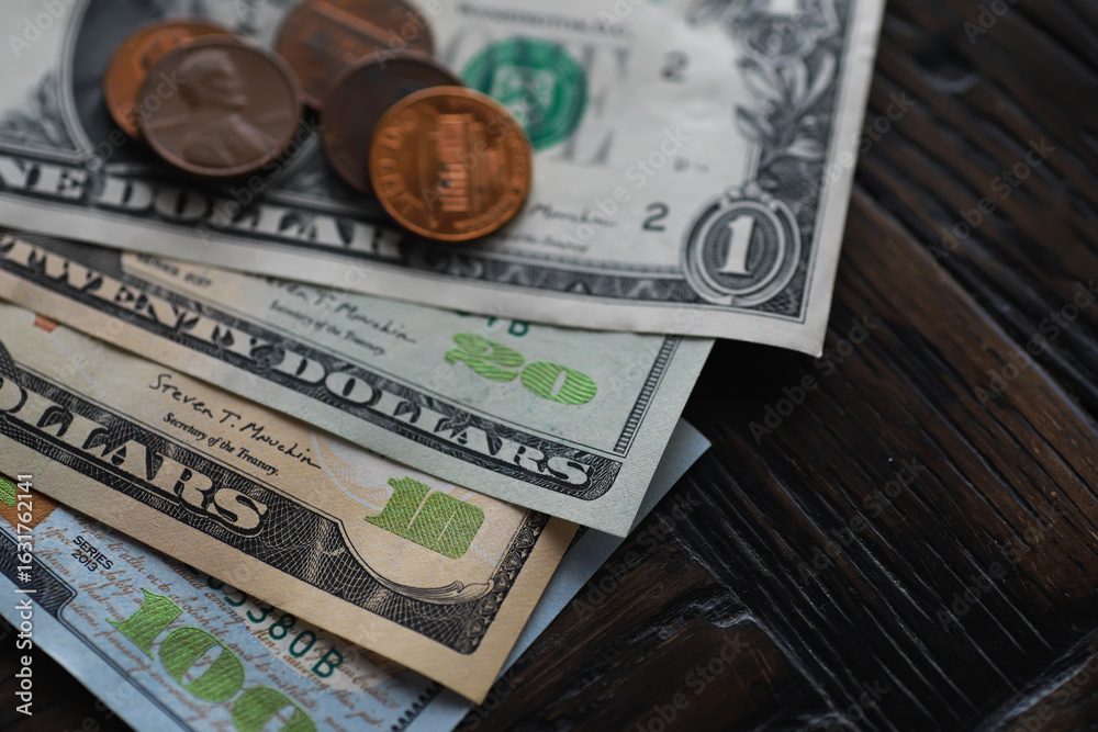 Fototapeta premium Close-Up of USD Currency Bills and Coins on Dark Wooden Surface - Financial Concept Photo