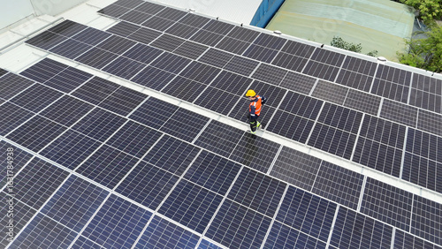 Worker inspects solar panels on factory roof during daylight