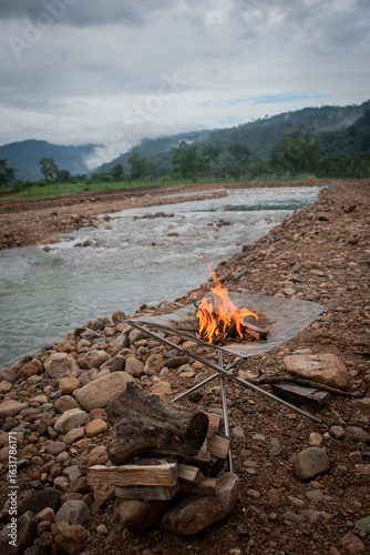 Camping bonfire by the river with mountain background