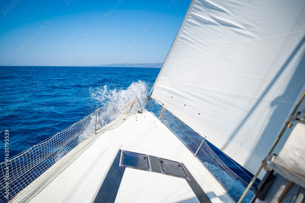 Obraz premium Bow of a sailing yacht cutting through the sea with sails fully open near Croatia. Freedom, motion, clean energy and slow travel on the open water.