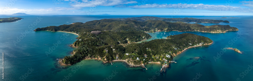 Fototapeta premium Aerial view of Kawau Island, New Zealand. Lush green islands are surrounded by turquoise water. Sailboats dot the bays, creating a scenic coastal landscape.