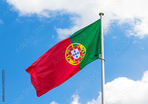 Traditional Portuguese national flag waiving in wind outside in park with blue sky in background