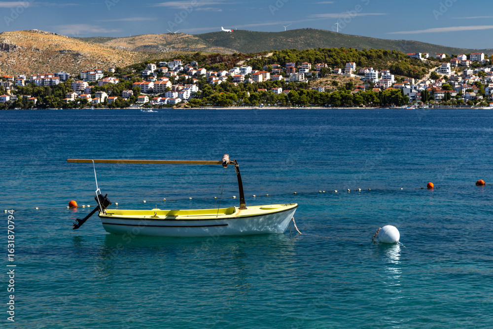 Fototapeta premium Water taxi docked at the beach on the island of Ciovo in Croatia, a low-flying plane landing at Split Airport