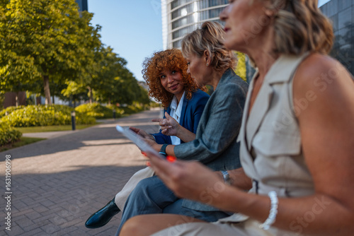 Businesswomen using tablet and discussing project outdoors