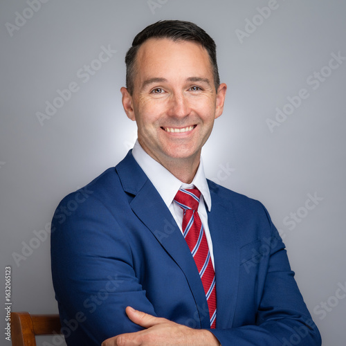 Portrait of white male professional in a blue suit and red tie. 