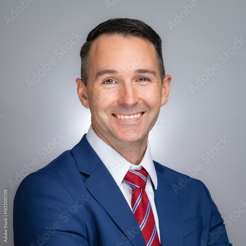 Portrait of white male professional in a blue suit and red tie. 