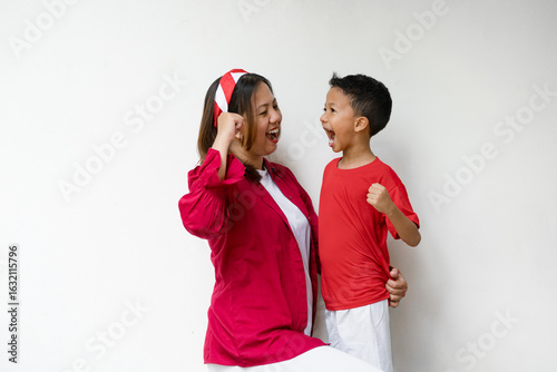 A happy Indonesian mother and child celebrating Independence Day together with joyful expressions. Dressed in red and white outfits, they show pride and unity while holding flags and smiling.