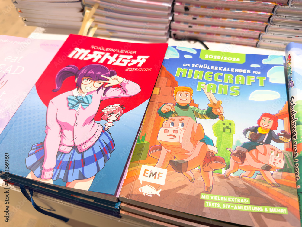 Naklejka premium Villach, Austria - August 05, 2025: Colorful manga and Minecraft themed school calendars displayed on a table, showcasing vibrant illustrations and engaging designs for students