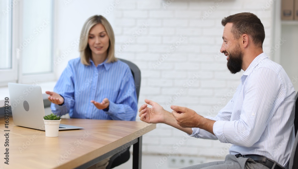 Obraz premium Smiling business partners working with laptop at table in office