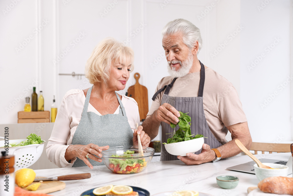 Elderly couple cooking together at table in kitchen Elderly couple cooking together at table in kitchen