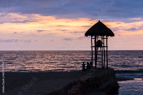 Tableau sur toile Hut lookout tower at sunset in Puerto Vallarta Mexico with silhouette of people