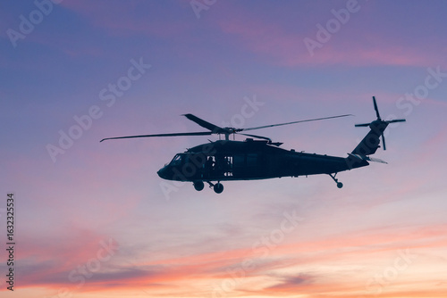 Foto A silhouette of a military helicopter flying against a bright blue sky, showcasing its structure and movement during an airborne operation