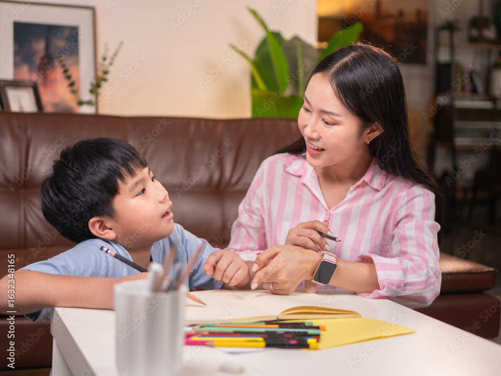 An Asian mother is helping her son do his homework in the living room. An Asian mother is helping her son do his homework in the living room.
