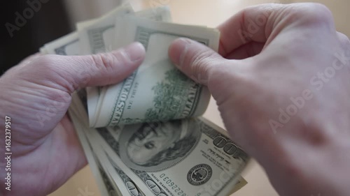 Hands counting 100-dollar bills over a table. Close-ups and different angles of cash handling, showing fingers flipping, stacking, and spreading US dollars.