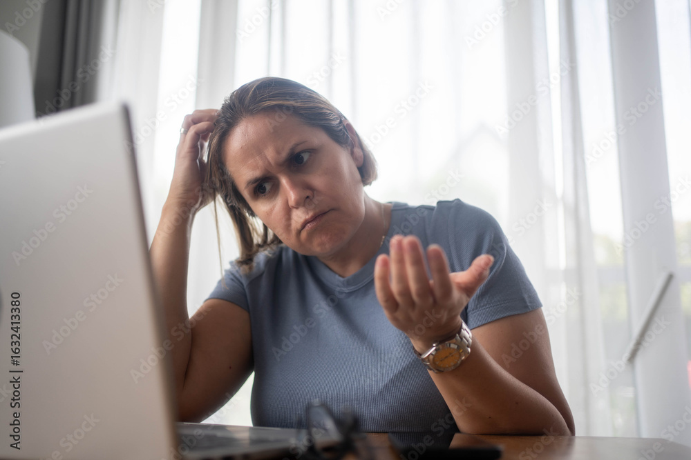 Obraz premium Confused businesswoman looking at laptop screen while working from home office, facing work challenge.