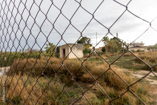 Abandoned house behind an iron fence with water drops.