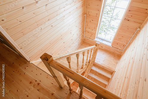 Schilderij op canvas wooden staircase leads down in a room with walls and ceiling clad in light wood paneling