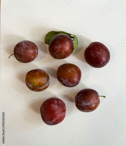 Seven plums on a white background.