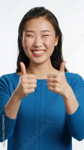 A vibrant medium close-up video of a diverse person with a radiant, genuine broad smile & sparkling eyes, enthusiastically giving two thumbs up against a clean, soft bokeh background with text space.