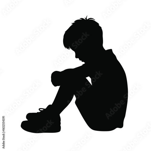 Silhouette of a young boy sitting with his head down