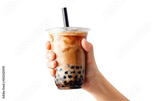 Hand holding bubble tea with tapioca pearls against a black background, close up
