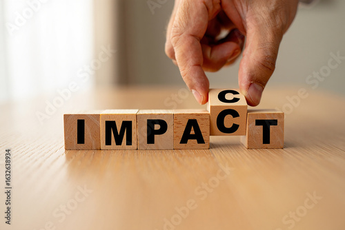 Hand places final letter to spell out the word impact