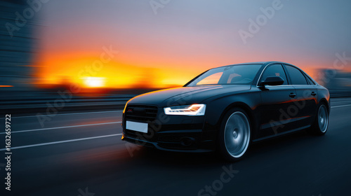 A black car is driving down a road at sunset