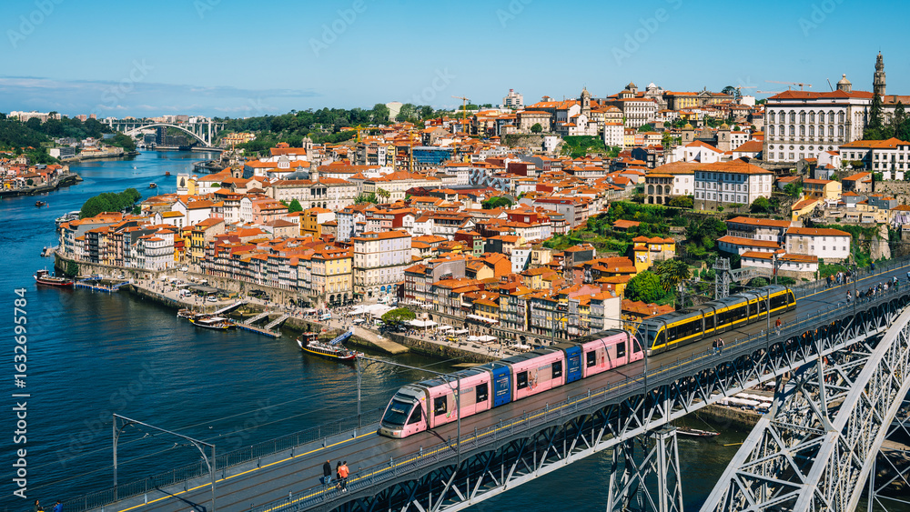 Obraz premium Scenic View of Porto Cityscape with Metro Train Crossing Iconic Bridge Over Douro River in Portugal