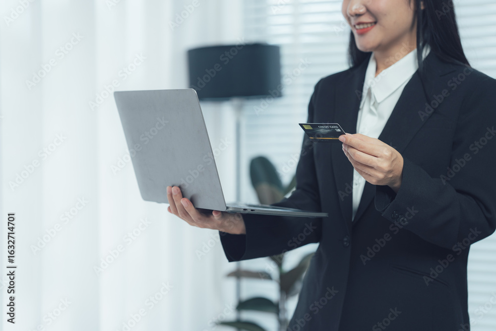 Online Shopping at Home: A woman dressed professionally is using a laptop and credit card at home, capturing the convenience of online shopping. Online Shopping at Home: A woman dressed professionally is using a laptop and credit card at home, capturing the convenience of online shopping.