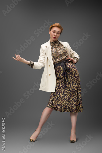 Confident woman in leopard print dress, fashion studio portrait