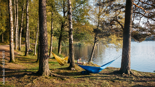 Scenic Lakeside Retreat with Vibrant Hammocks Amidst Serene Forest on a Tranquil Afternoon
