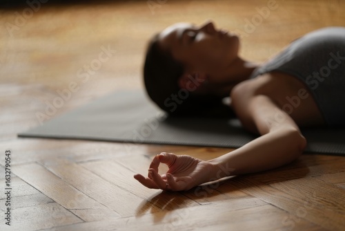 Woman practicing yoga nidra pose for relaxation and stress relief on yoga mat at home