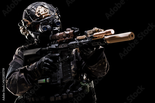 Photos Professional soldier in tactical gear aiming a rifle in low light