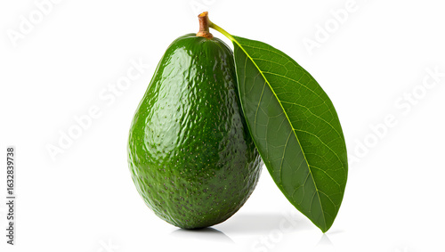 A single ripe green avocado with two fresh leaves attached isolated on a stark black background