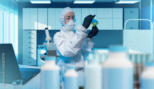 Obraz na płótnie Scientist in protective suit analyzing chemical liquid in laboratory, working with high safety standards in biotech, pharmaceutical, or medical research