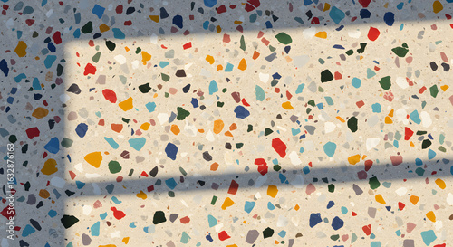 A close-up of terrazzo flooring shows a mix of colorful chips in a light tan matrix, with shadows.