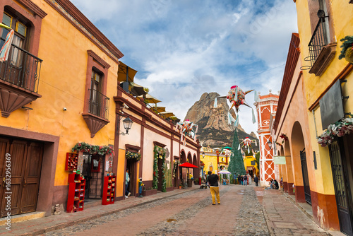 Colorful colonial buildings and festive piñatas below iconic Peña de Bernal in Bernal, Mexico