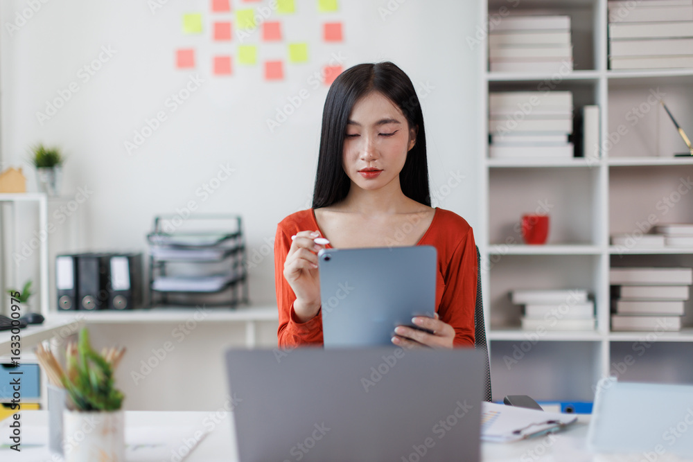 Asian Female business person using digital tablet and laptop or remote working at office, looking at digital tablet learning training, studying online thinking Financial and Accounting concept.
Asian Female business person using digital tablet and laptop or remote working at office, looking at digital tablet learning training, studying online thinking Financial and Accounting concept.